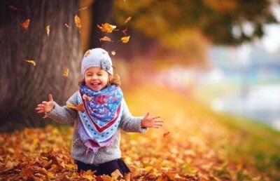 Smiling little girl playing in leaves. 